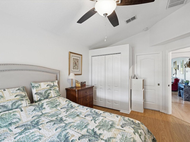 bedroom with lofted ceiling, light wood finished floors, visible vents, and a closet