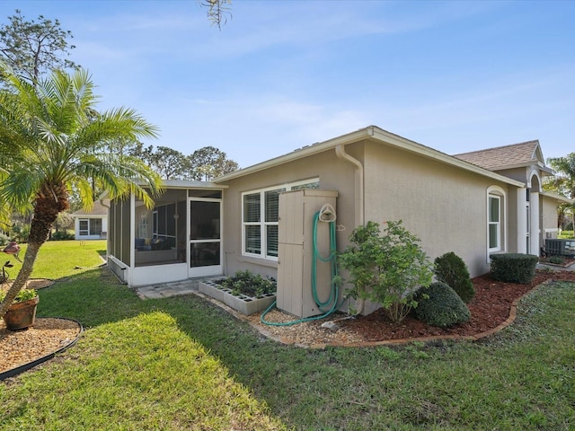 view of home's exterior with a lawn, cooling unit, a sunroom, and stucco siding