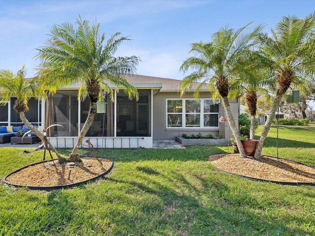 rear view of property with a lawn, a sunroom, and stucco siding