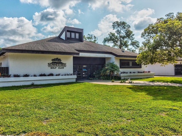 view of front of house with a shingled roof, a front lawn, and stucco siding