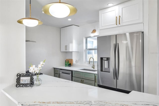 kitchen with pendant lighting, sink, light stone countertops, white cabinetry, and stainless steel appliances