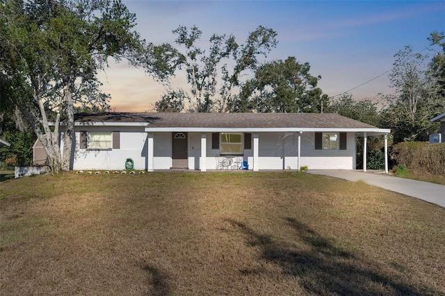 ranch-style home with a lawn, covered porch, and a carport