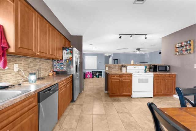 kitchen with backsplash, ceiling fan, light tile patterned floors, appliances with stainless steel finishes, and kitchen peninsula