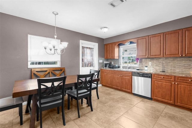 kitchen with light stone countertops, stainless steel dishwasher, sink, a chandelier, and hanging light fixtures