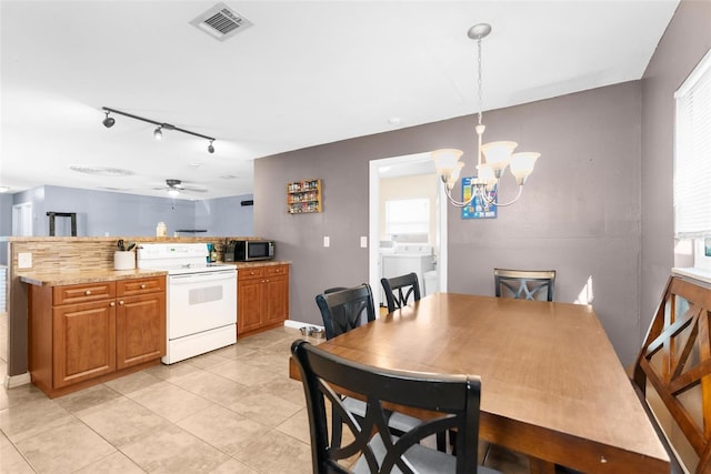 kitchen featuring ceiling fan with notable chandelier, hanging light fixtures, washing machine and dryer, light stone countertops, and white range with electric stovetop