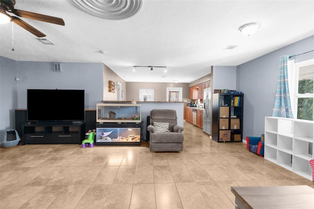 living room featuring light tile patterned floors, a textured ceiling, and ceiling fan