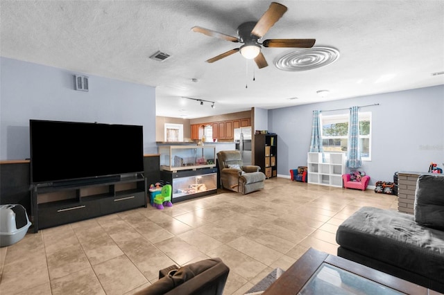 living room featuring a textured ceiling, ceiling fan, light tile patterned floors, and track lighting