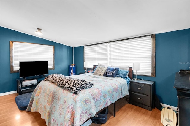 bedroom with light hardwood / wood-style floors and lofted ceiling