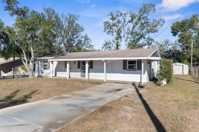 single story home with covered porch, a front yard, and a storage unit