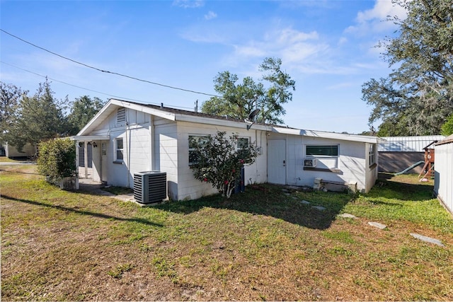 rear view of house featuring cooling unit and a yard