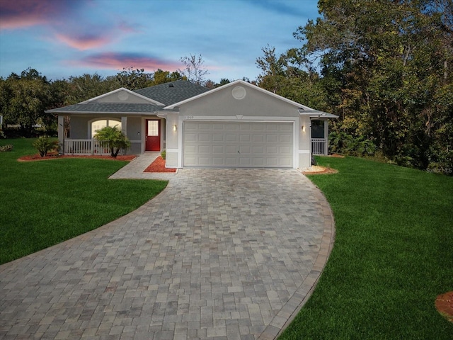 single story home with a lawn, a garage, and covered porch