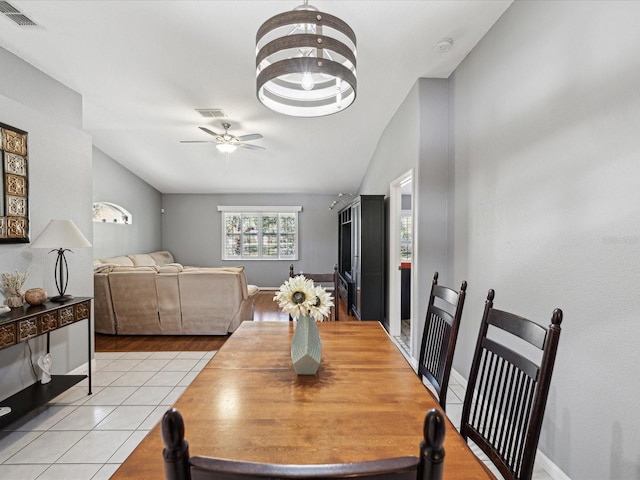 dining area featuring lofted ceiling, light tile patterned floors, and ceiling fan with notable chandelier