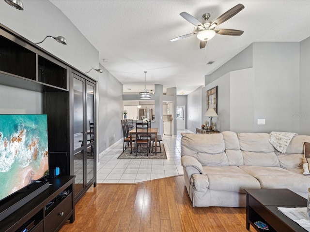 living room featuring ceiling fan with notable chandelier and light hardwood / wood-style flooring