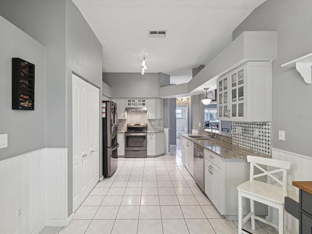 kitchen featuring backsplash, dark stone counters, sink, appliances with stainless steel finishes, and white cabinetry