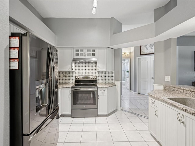 kitchen with light stone countertops, light tile patterned floors, decorative backsplash, white cabinets, and appliances with stainless steel finishes