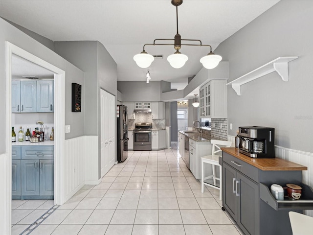 kitchen featuring tasteful backsplash, stainless steel appliances, sink, white cabinets, and light tile patterned flooring