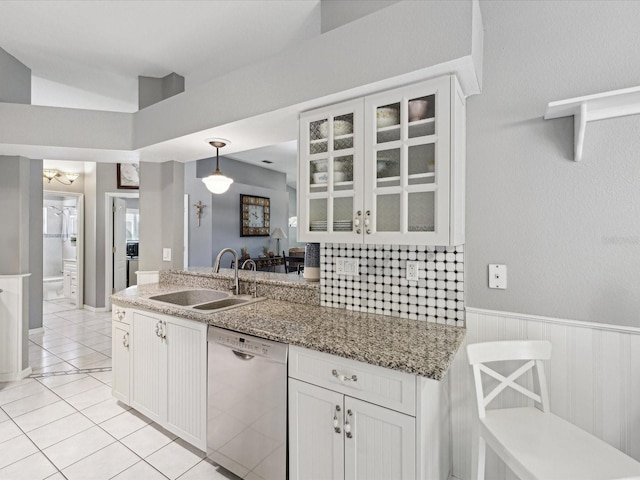 kitchen featuring pendant lighting, dishwasher, sink, light tile patterned flooring, and white cabinetry