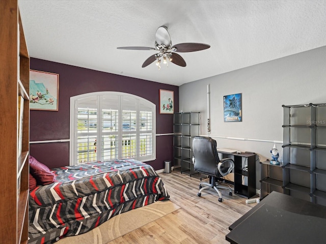 bedroom with ceiling fan, a textured ceiling, and light wood-type flooring