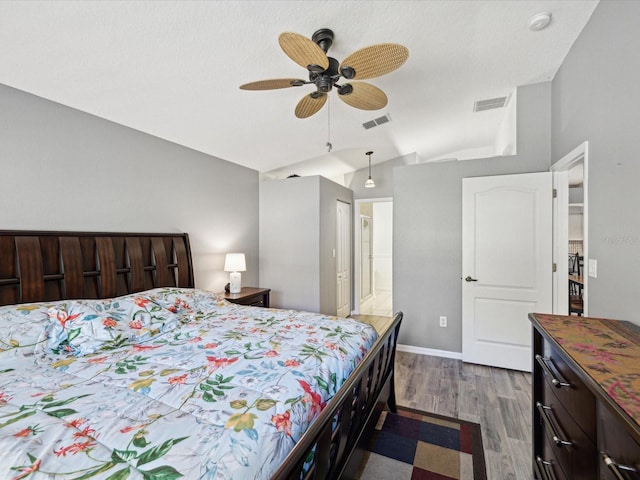 bedroom with ceiling fan, wood-type flooring, lofted ceiling, and connected bathroom