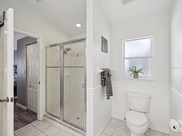 bathroom featuring tile patterned flooring, toilet, and an enclosed shower