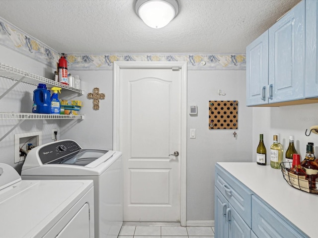 washroom with cabinets, separate washer and dryer, a textured ceiling, and light tile patterned floors