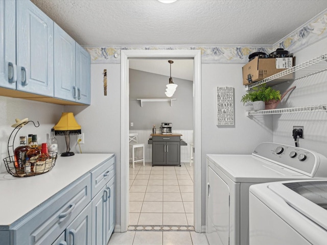 washroom featuring washer and clothes dryer, light tile patterned floors, cabinets, and a textured ceiling