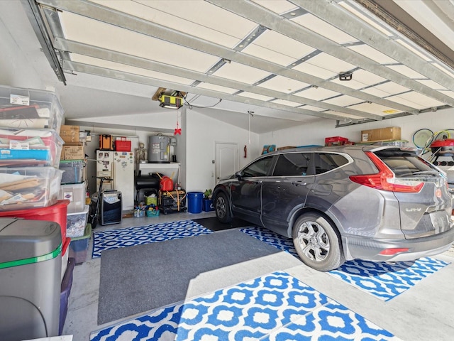 garage with white fridge, a garage door opener, and water heater