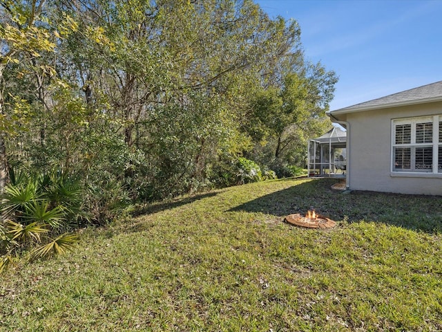 view of yard with glass enclosure and an outdoor fire pit