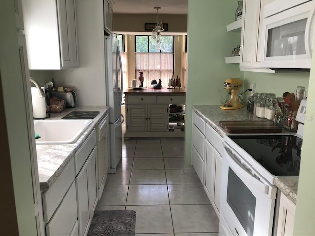 kitchen featuring pendant lighting, white appliances, white cabinets, and light tile patterned floors