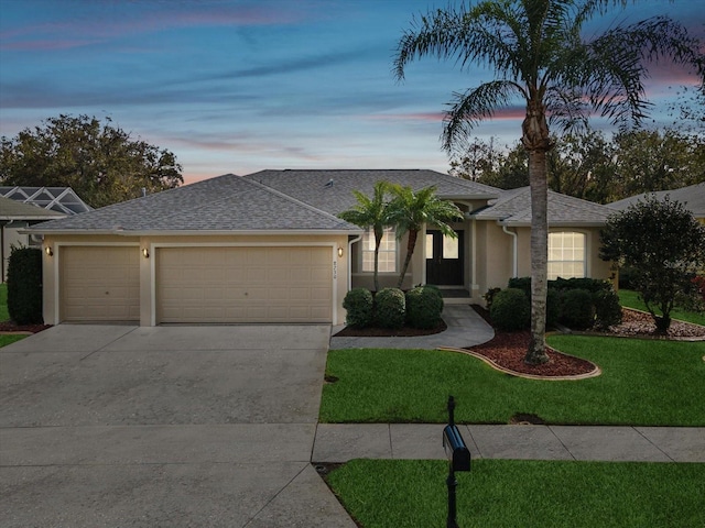 ranch-style house featuring a garage and a lawn