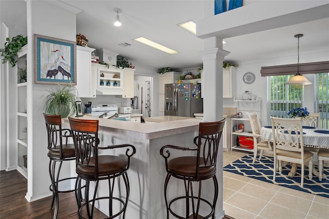 kitchen with kitchen peninsula, a kitchen breakfast bar, white range with electric cooktop, stainless steel fridge with ice dispenser, and white cabinetry