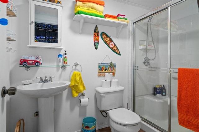 bathroom with ornamental molding, a shower with shower door, and toilet