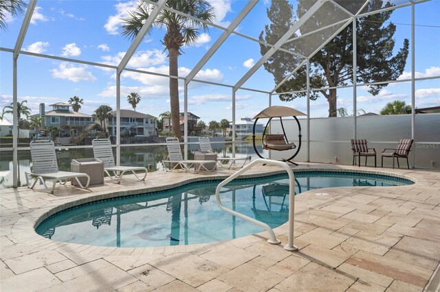 view of pool featuring glass enclosure, a patio area, and a water view