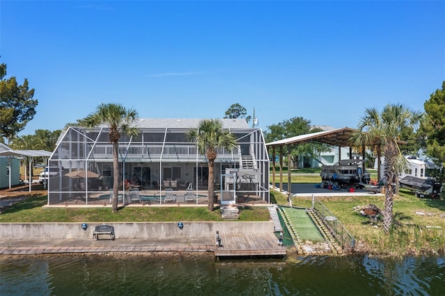 rear view of property with a lanai, a water view, and a yard