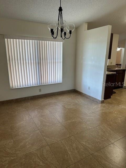 unfurnished dining area featuring light tile patterned flooring, a textured ceiling, and a chandelier