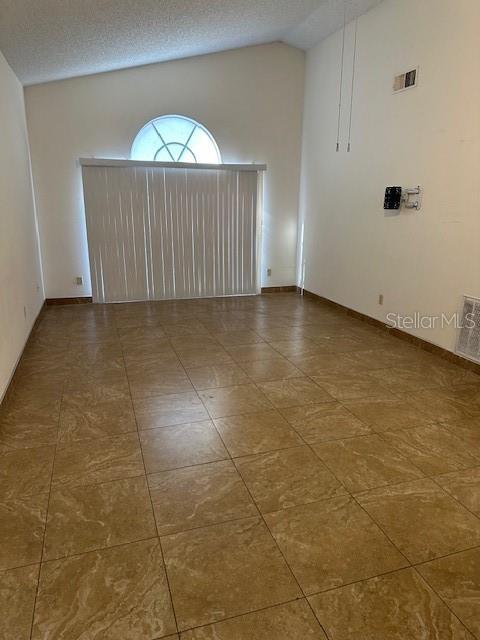 empty room with a textured ceiling and vaulted ceiling