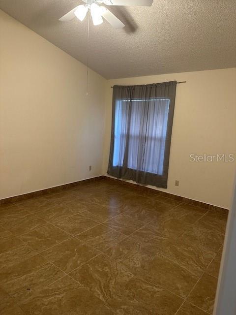 empty room with ceiling fan and a textured ceiling