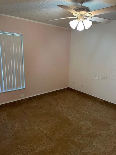 spare room with ceiling fan, ornamental molding, and a textured ceiling