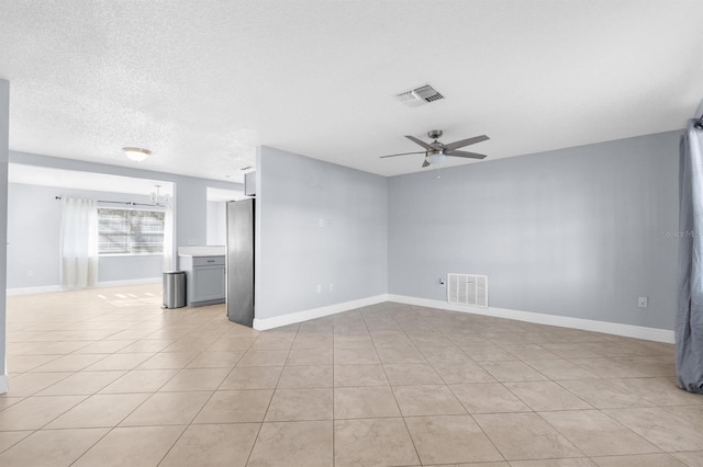 empty room featuring ceiling fan, light tile patterned floors, and a textured ceiling