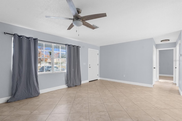 empty room featuring light tile patterned floors, a textured ceiling, and ceiling fan