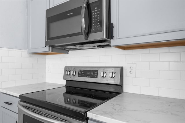 kitchen with decorative backsplash, range with electric cooktop, gray cabinetry, and light stone countertops