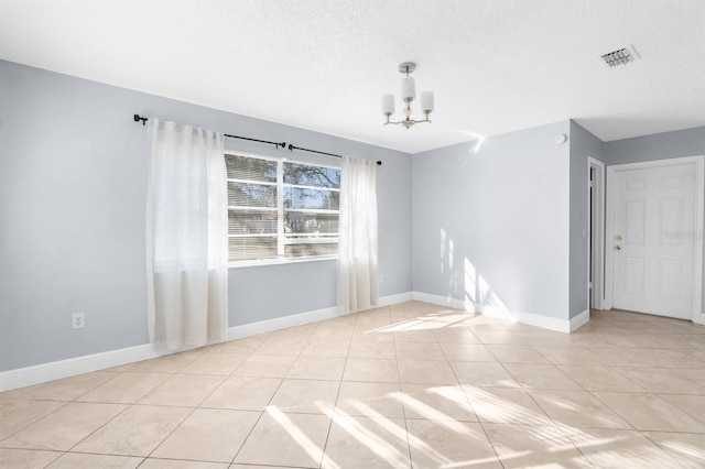 tiled empty room featuring a chandelier and a textured ceiling