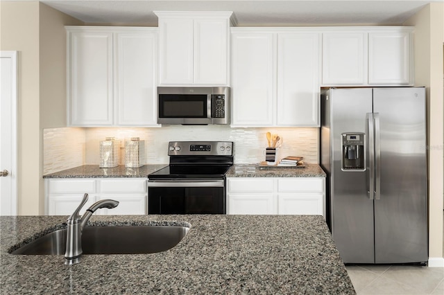 kitchen with appliances with stainless steel finishes, sink, white cabinetry, and dark stone countertops