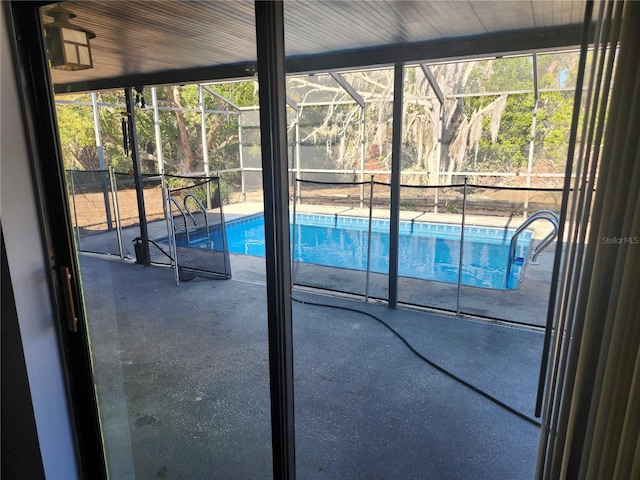 view of pool with glass enclosure and a patio