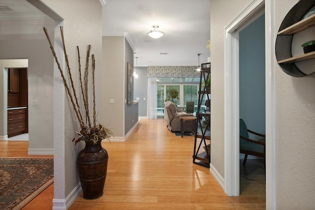 hallway featuring light wood-type flooring and ornamental molding