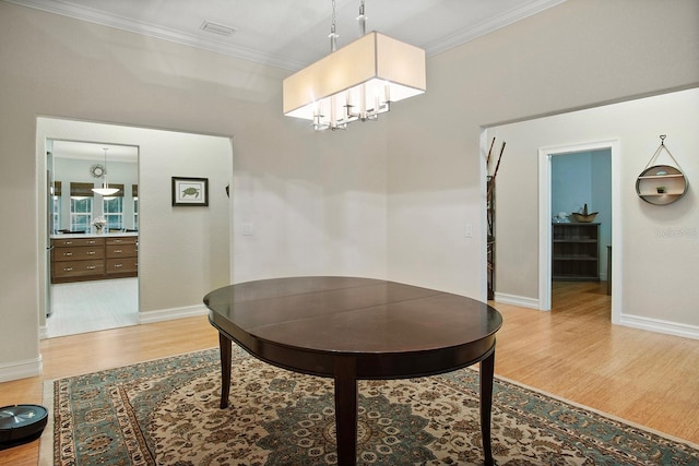 dining room with a chandelier, ornamental molding, and light wood-type flooring