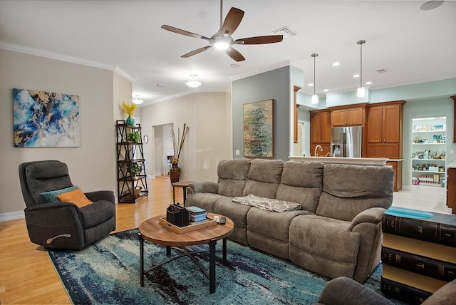 living room featuring ceiling fan, ornamental molding, and light hardwood / wood-style flooring