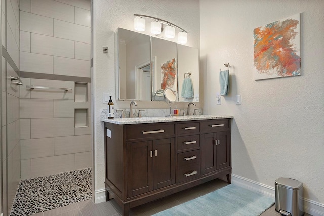 bathroom featuring tile patterned flooring, vanity, and tiled shower