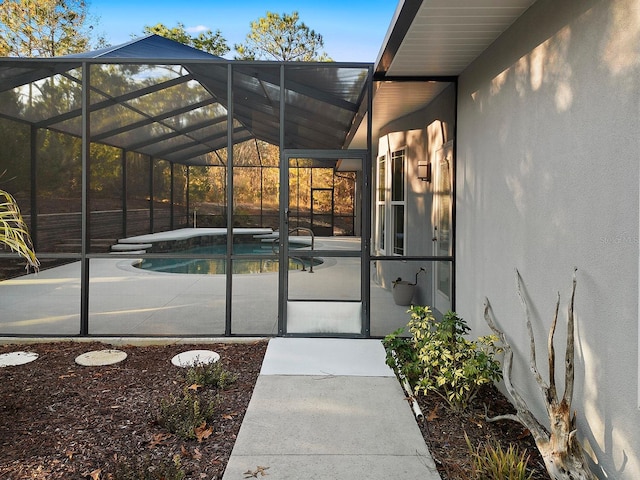 view of exterior entry with a patio and a pool with hot tub