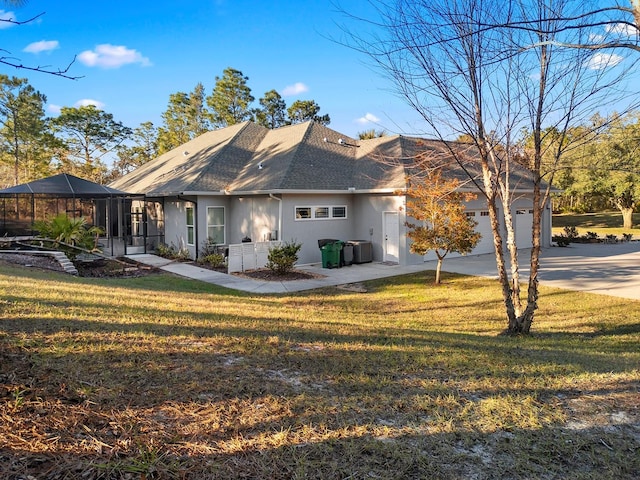 view of front of property featuring central AC unit, a lanai, a garage, and a front yard